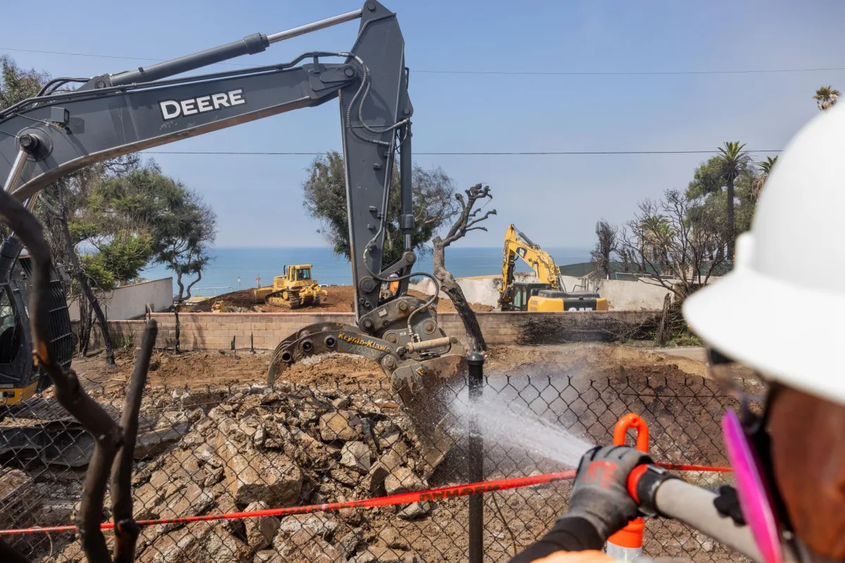 Machine clearing debris from a fire-damaged structure
