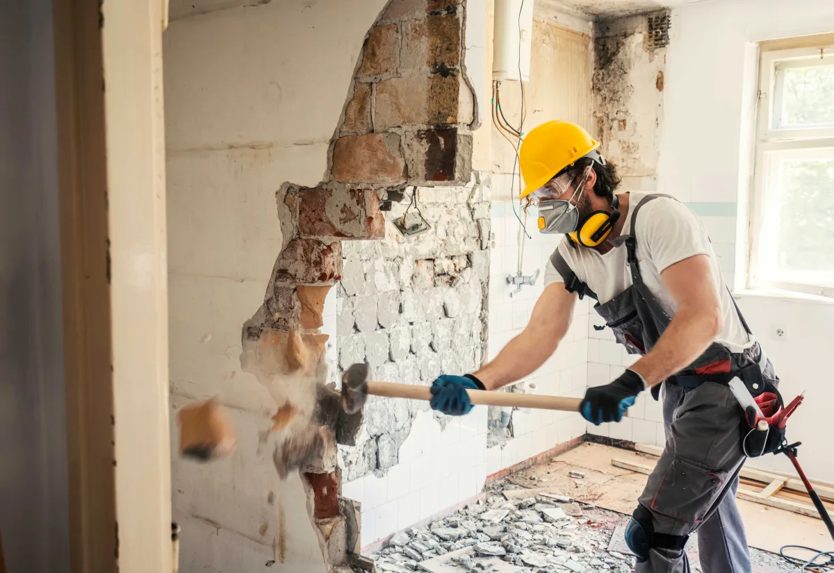 Worker removing drywall during an interior demolition